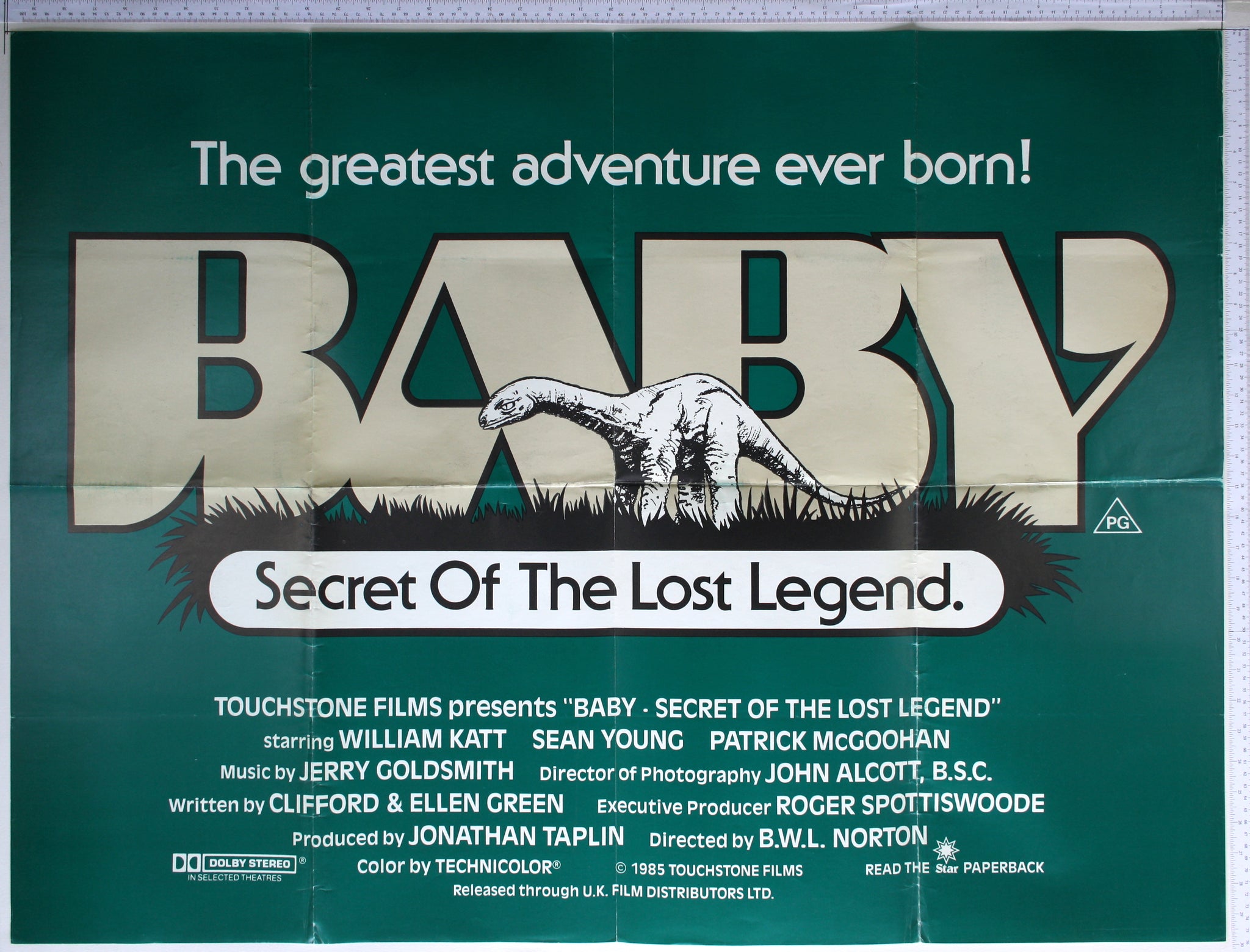 Graphic poster of the title behind artwork of the baby dinosaur on dark grass, all against dark green background