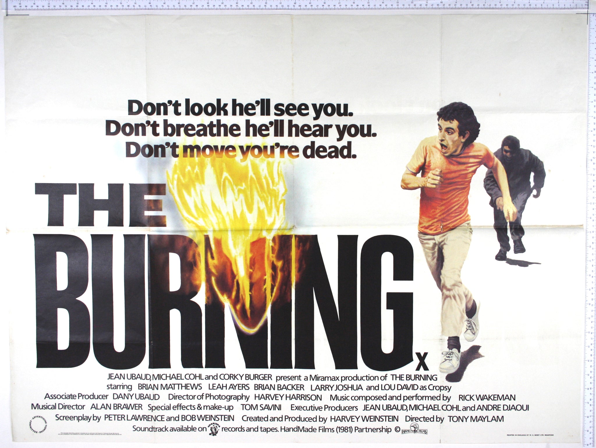 At right a boy in T Shirt running terrified from a shadowy figure, with The Burning title to left and centre beginning to burst into flames.