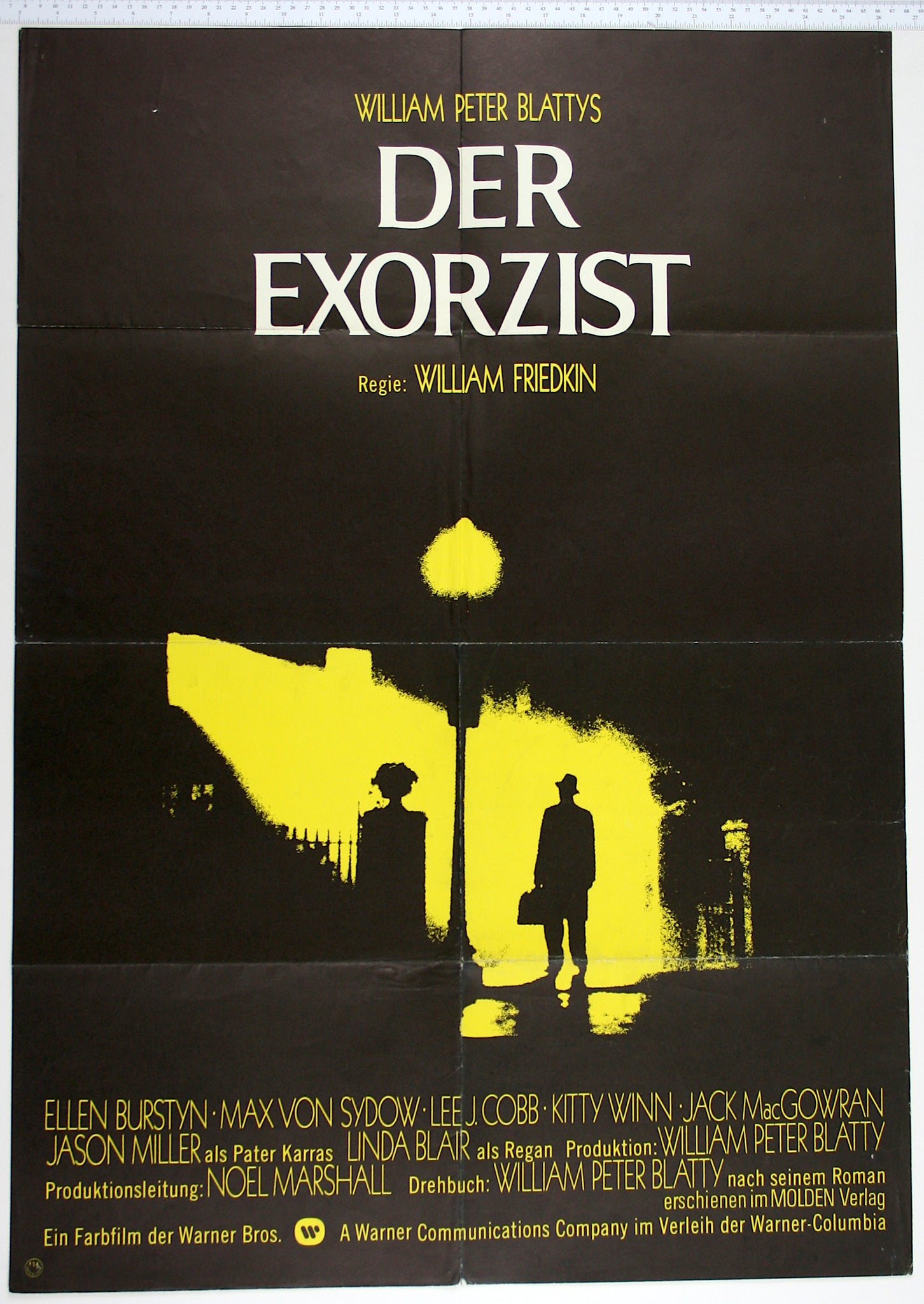 High contrast yellow image of exorcist arriving at house. Street lamp casts shaft of light, making a silhouette of the priest.