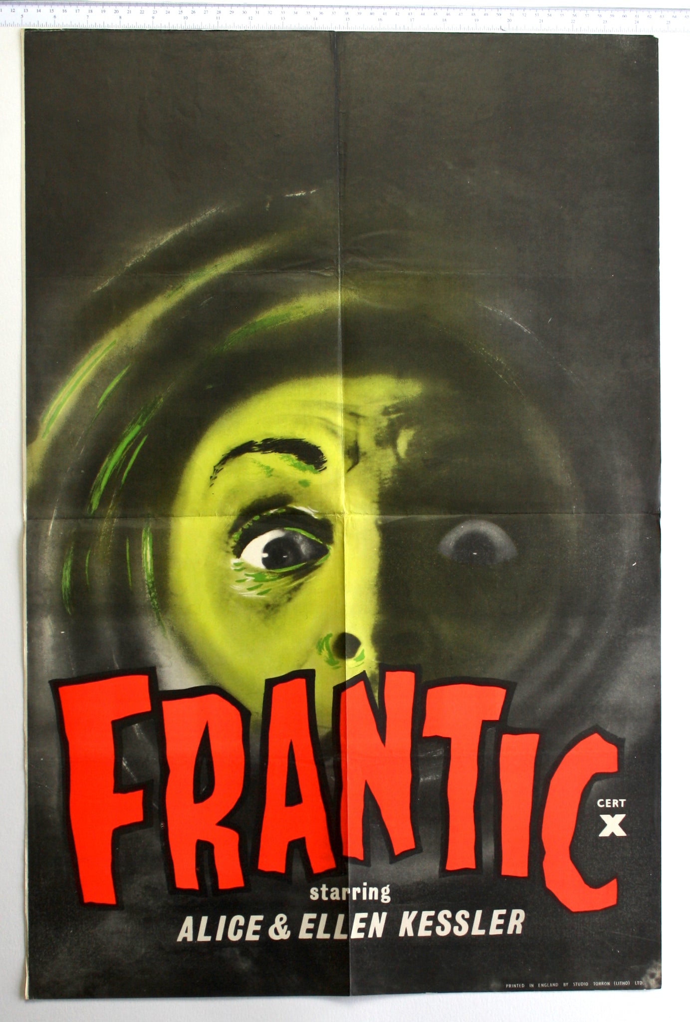 Within a black swirl, green highlights reveal a face with wide staring eyes. The title is in a rough freestyle font in red.