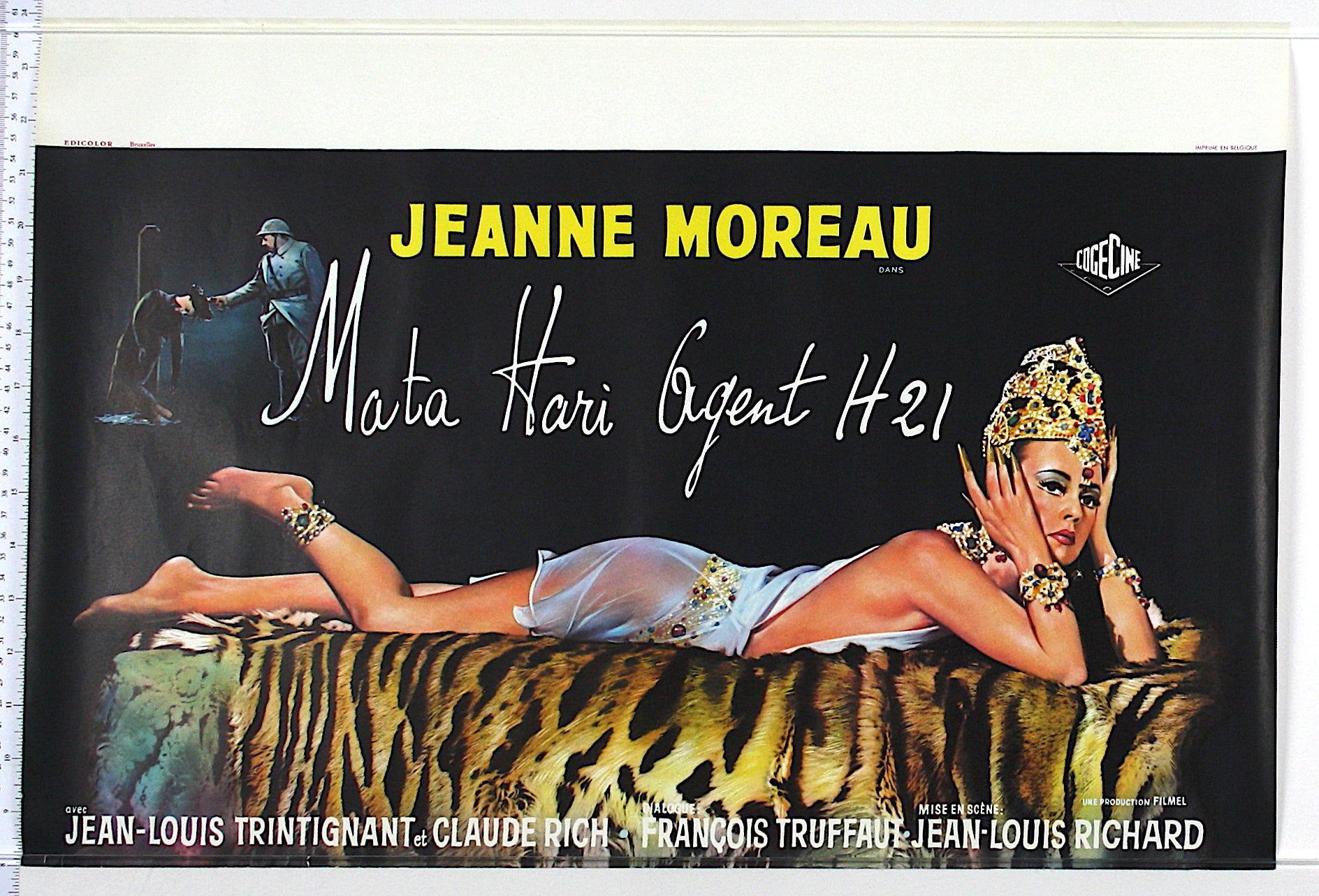 Artwork of Mata Hari in headdress and skimpy costume. She lies on tiger skin bed, at top man is executed by soldier.