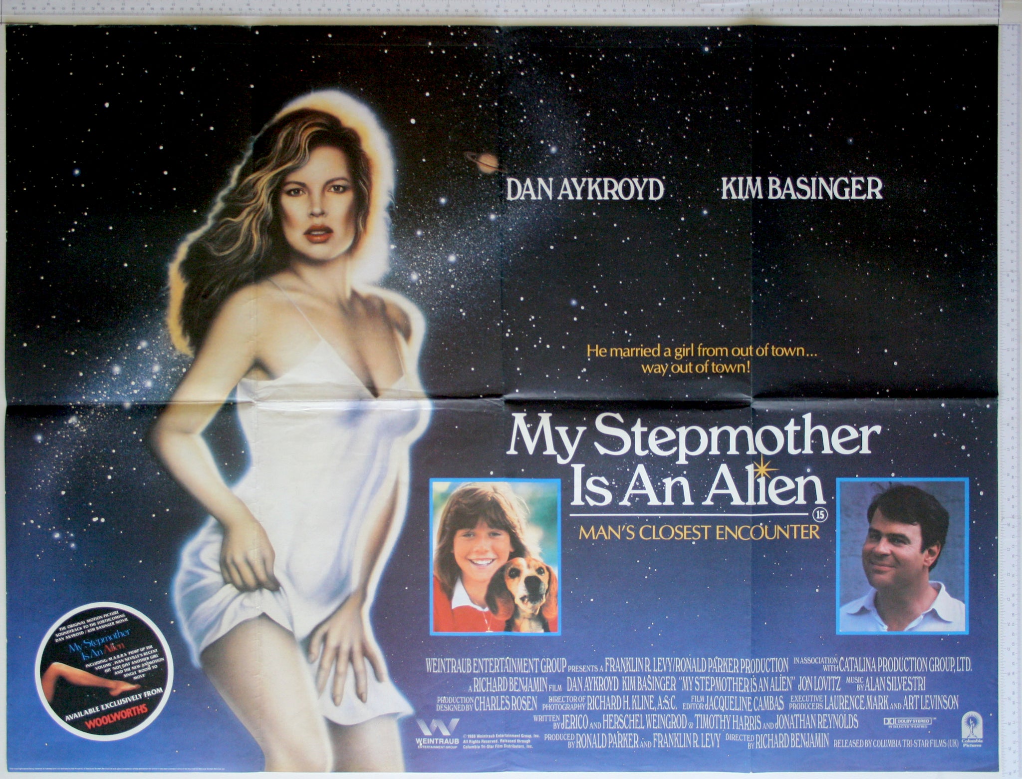 On star background, airbrushed figure of Basinger, with two inset photos of girl and man.