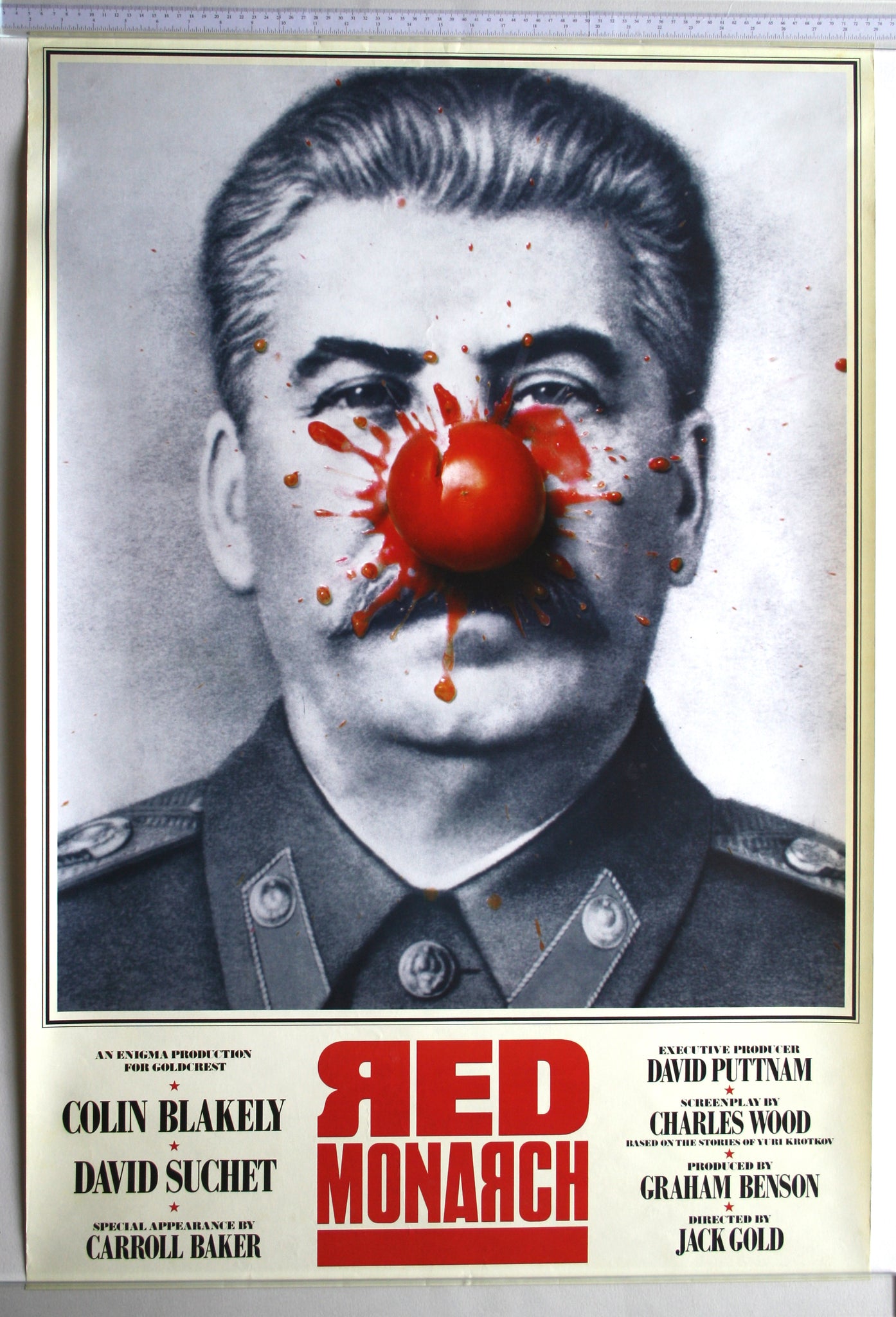 B+W photo of Stalin with thrown tomato landing in centre, giving him clown-like appearance. Mock-cyrillic text.