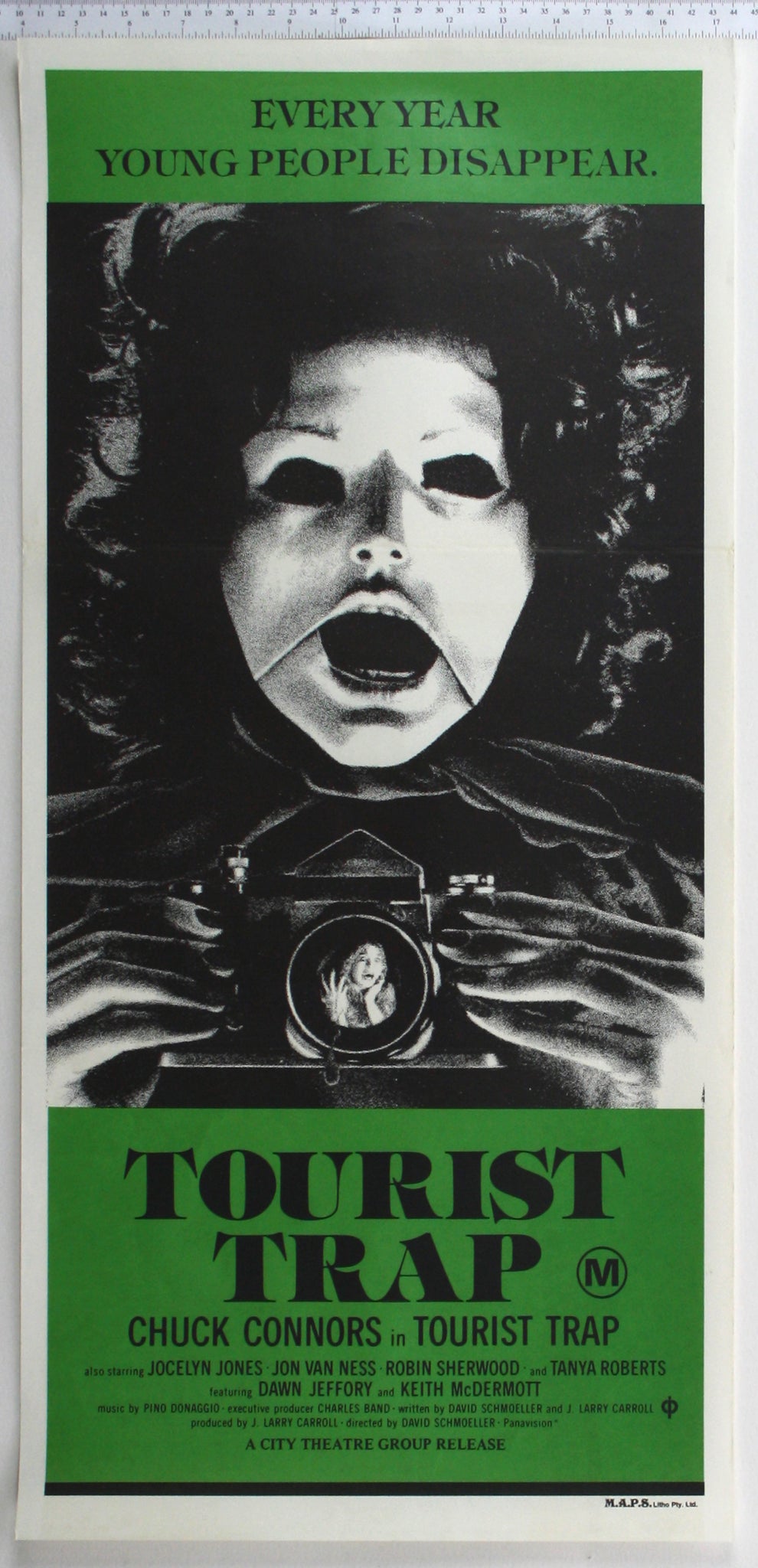 B+W artwork on green, inset figure of blank-eyed mannequin with human mouth, holding camera reflecting terrified woman.